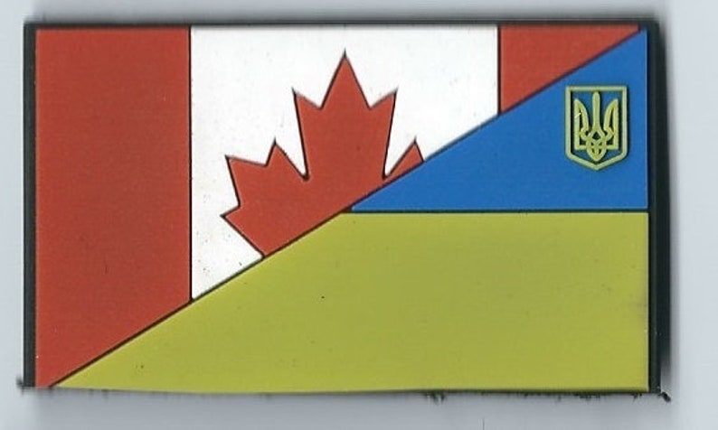 May include: A patch with the Canadian flag and the Ukrainian flag. The Canadian flag is red and white with a maple leaf. The Ukrainian flag is blue and yellow with a trident.