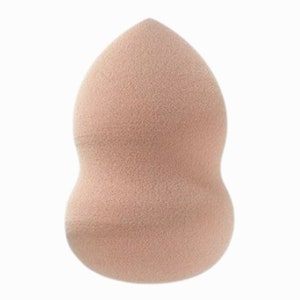 Op de afbeelding: Een lichtroze make-up spons in de vorm van een traan. De spons is zacht en heeft een textuur.