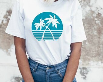 May include: White t-shirt featuring a blue and white graphic of two palm trees against a sunset backdrop. The design is in a retro style.