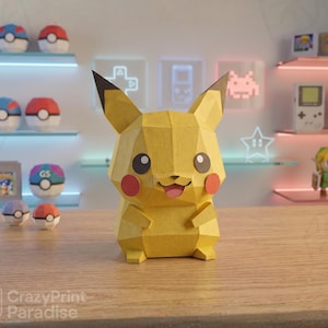 May include: A yellow, low-poly papercraft figure of the character Pikachu, featuring pointed ears with black tips, round red cheeks, and a smiling expression with an open mouth. The figure has a faceted, geometric design and stands on a flat surface.