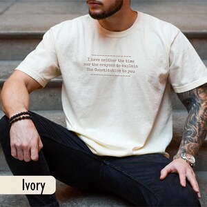 May include: Ivory-colored t-shirt with the text "I have neither the time nor the crayons to explain The Constitution to you." The shirt is a neutral color and has a relaxed fit. The word "Ivory" is printed at the bottom.