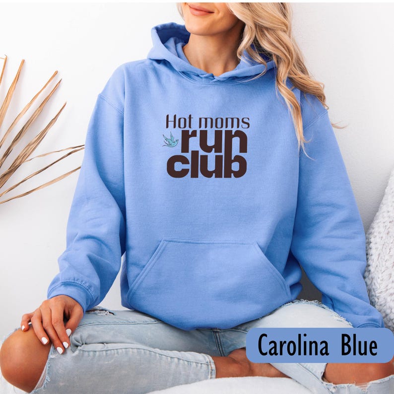 May include: Carolina Blue hoodie with the text "Hot moms run club" in brown. The hoodie has a front pocket and a hood. The text is accompanied by a small green bird graphic.