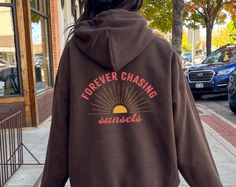 May include: Brown hooded sweatshirt with a graphic print on the back that says "FOREVER CHASING sunsets" with a stylized sun graphic.