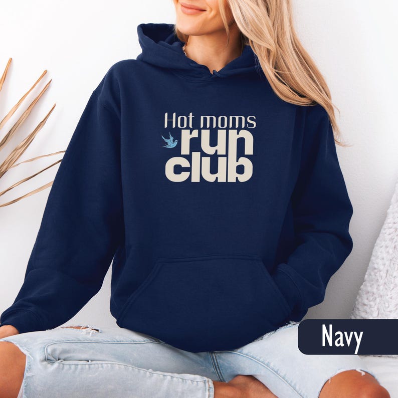 May include: Navy blue hooded sweatshirt with the text "Hot moms run club" in a cream color. The sweatshirt has a front pocket and a drawstring hood. The word "Navy" is displayed in a dark blue rectangle at the bottom right.
