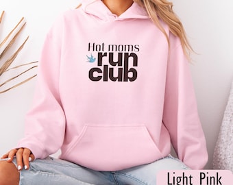 May include: Light pink hoodie with a front pocket and drawstring hood. The front features the text "Hot moms run club" in black and a blue bird graphic. The words "Light Pink" are at the bottom.