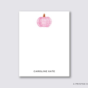 Peut inclure: Une carte blanche avec une illustration de citrouille en vichy rose et blanc et le texte "CAROLINE KATE" imprimé en noir.