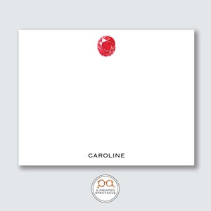 May include: White stationery card with a red gemstone illustration and the name "CAROLINE" printed in black text at the bottom.