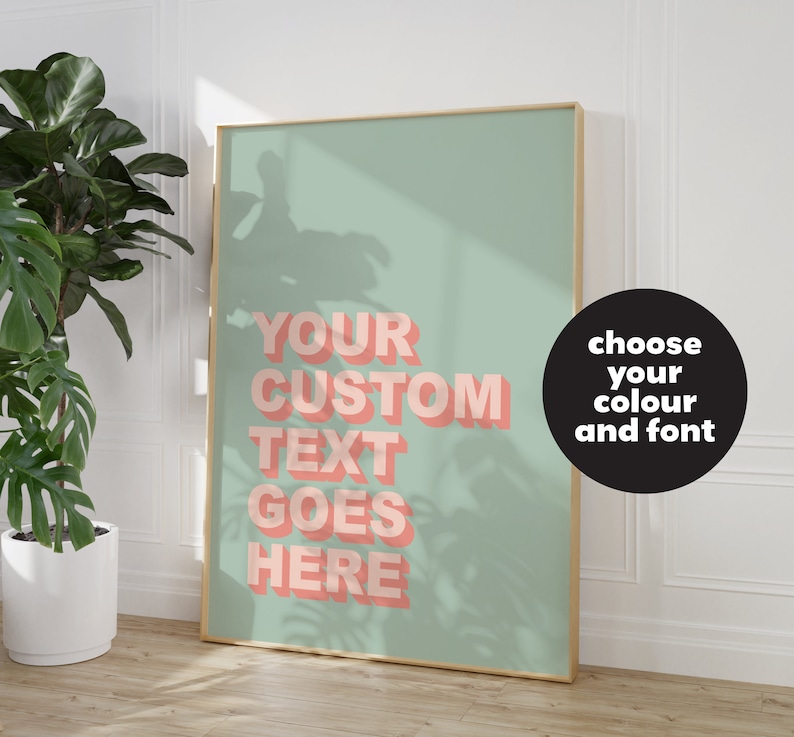 May include: A framed poster with a light green background and a pink text overlay that says "YOUR CUSTOM TEXT GOES HERE". The text is in a 3D style. A black circle with white text says "choose your colour and font".