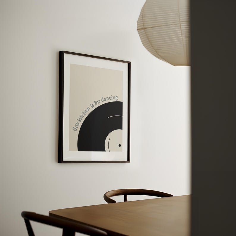 Może przedstawiać: Czarno-biały wydruk w ramie z tekstem "this kitchen is for dancing" i grafiką czarnej płyty winylowej.