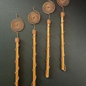 Tensor Tesla Copper Antenna placed in garden soil near green plants, symbolizing natural energy flow, root vitality, and sustainable gardening concept.