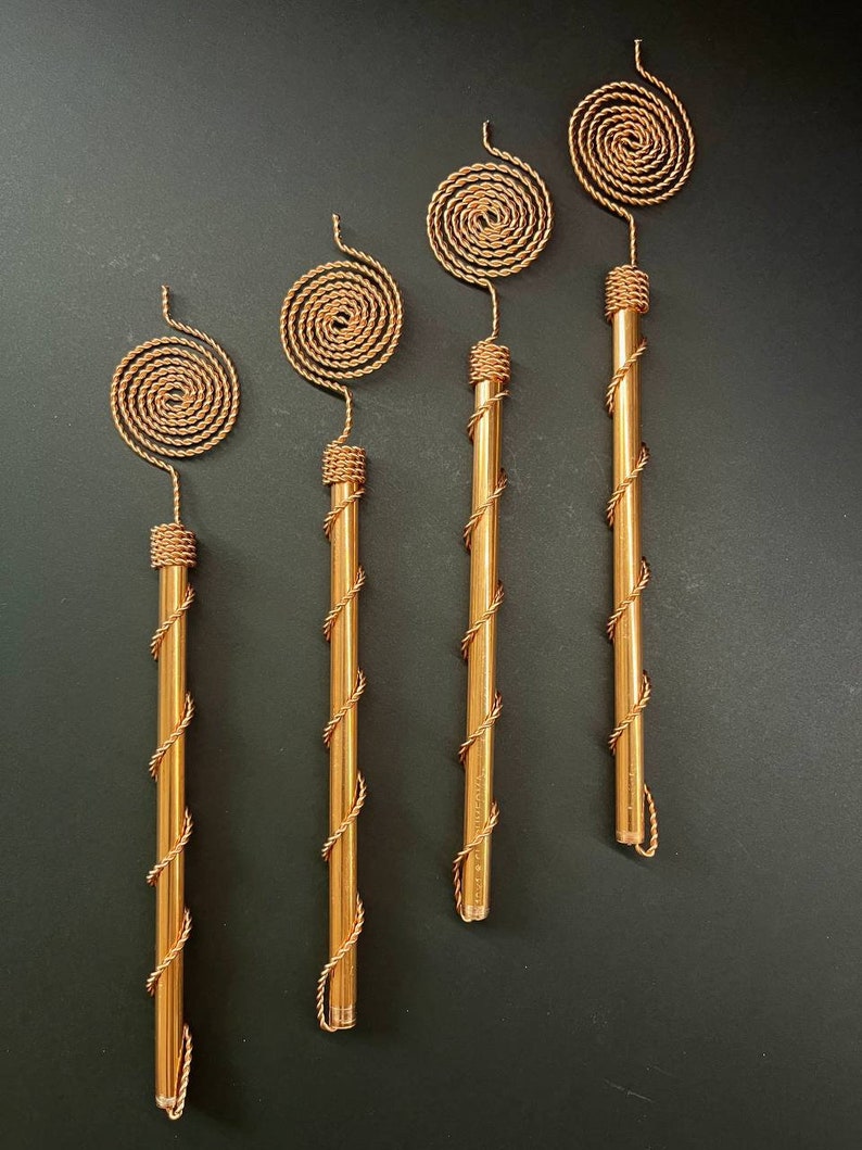 Tensor Tesla Copper Antenna placed in garden soil near green plants, symbolizing natural energy flow, root vitality, and sustainable gardening concept.