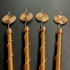 Handcrafted copper spiral antennas aligned on dark background for detail view