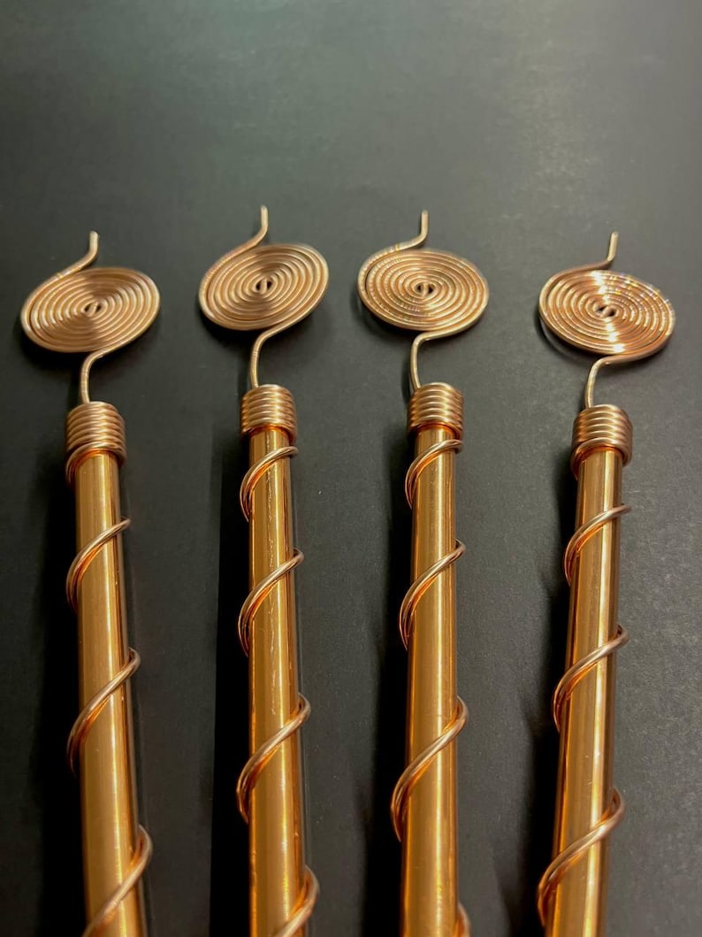 Handcrafted copper spiral antennas aligned on dark background for detail view