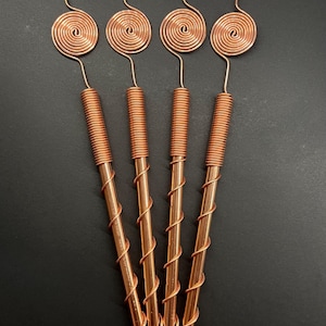 May include: Four copper wire spiral stirrers with a rounded top. The stirrers are arranged in a fan shape.