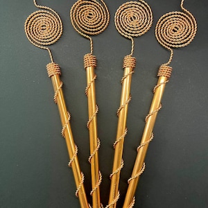 May include: Four gold-colored metal wands with a spiral design at the top. The wands are about 10 inches long.