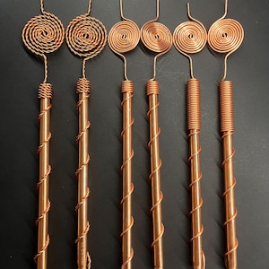 Copper antennas arranged in a straight row showcasing different Tesla spiral styles