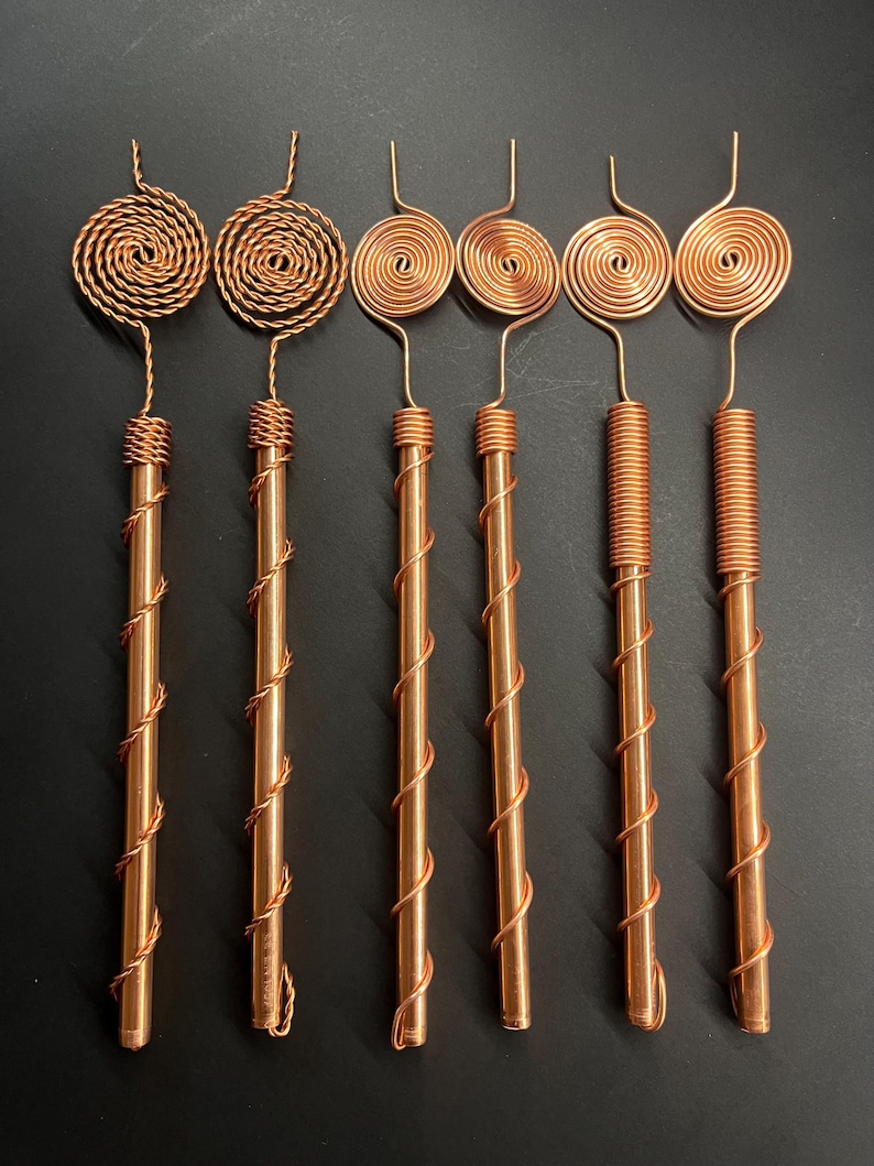 Copper antennas arranged in a straight row showcasing different Tesla spiral styles