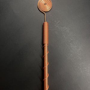 Macro view of copper spiral showing detailed winding and Tesla-inspired craftsmanship