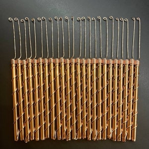 May include: A set of 20 copper crochet hooks with a silver hook at the end of each hook. The hooks are arranged in a row and are all the same size.
