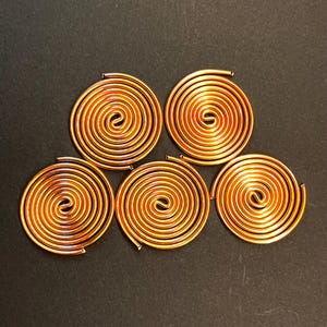 May include: Six copper wire coils arranged in a pyramid shape on a black background.