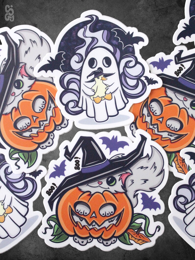 Op de afbeelding: Vier Halloween-stickers met een witte kat met een heksenhoed, een geest die een kleine gele eend vasthoudt en twee witte katten in pompoenen. De stickers hebben een witte achtergrond met zwarte vleermuizen en het woord "Boo!" op sommige van hen.