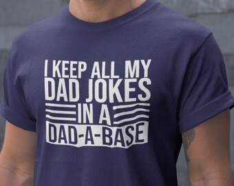 May include: A navy blue t-shirt with white text that reads "I keep all my dad jokes in a dad-a-base".