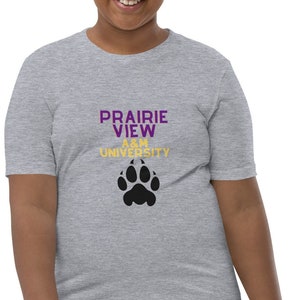 Könnte beinhalten: Ein graues T-Shirt für Jugendliche mit einem schwarzen Pfotenabdruck und dem Text "Prairie View A&M University" in Lila und Gold.