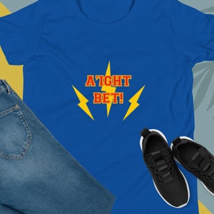 May include: A blue t-shirt with the text "A'ight Bet!" in red with yellow lightning bolts on either side.
