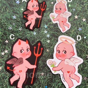 May include: Four stickers featuring a pink cherub with wings. Two stickers depict the cherub as a devil with a red trident and horns. The other two stickers depict the cherub as an angel with a halo and flowers. The stickers have a black background and a white background.