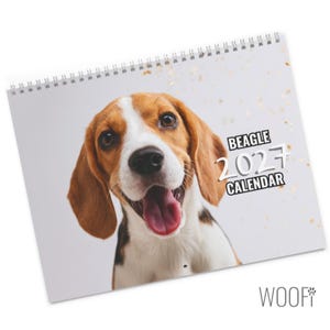 May include: A spiral-bound wall calendar featuring a portrait of a brown, white, and black beagle dog with its mouth open. The text on the cover reads BEAGLE 2027 CALENDAR. The background is light grey with scattered gold-coloured confetti accents.