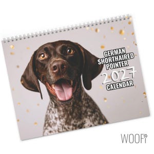 May include: A spiral-bound wall calendar featuring a portrait of a brown and white German Shorthaired Pointer with its tongue out. The cover includes the text GERMAN SHORTHAIRED POINTER 2027 CALENDAR against a light background with gold confetti.