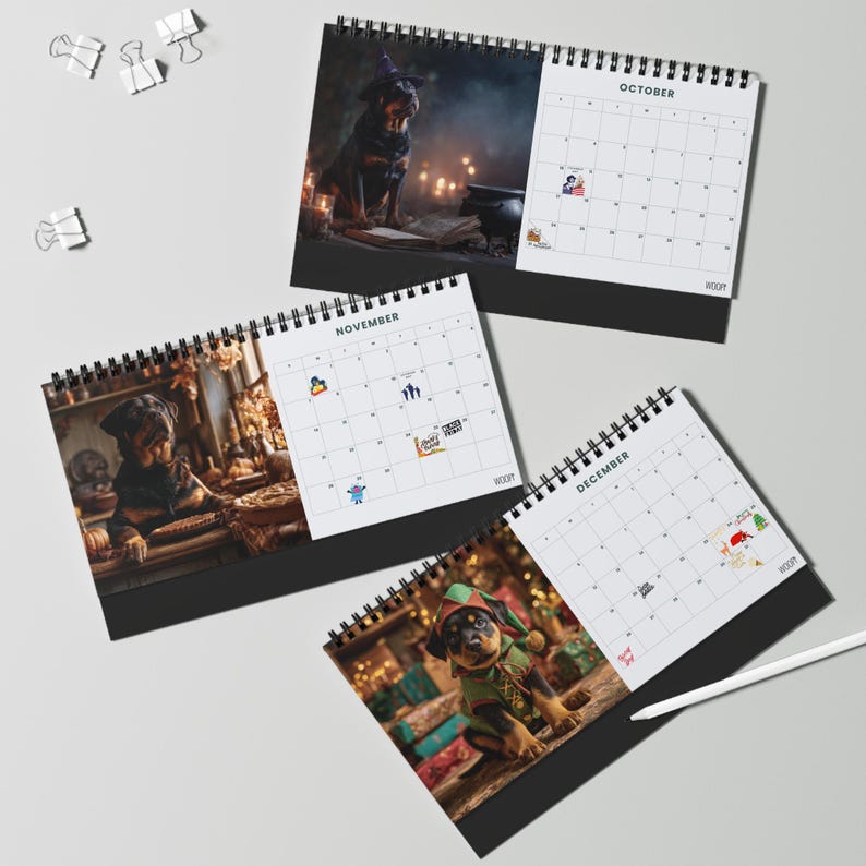 K&ouml;nnte beinhalten: Drei spiralgebundene Tischkalender f&uuml;r die Monate Oktober, November und Dezember. Jede Seite zeigt einen Rottweiler-Welpen in einem thematischen Kost&uuml;m, darunter eine Hexe, ein B&auml;cker und ein Elf, sowie ein Datumsraster und kleine Symbole.