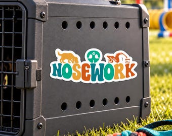 May include: A black plastic dog crate featuring a colourful sticker with the text NOSEWORK in a bold font. The sticker includes a yellow dog silhouette, a teal dog nose icon, and an orange graphic of a dog sniffing a container.