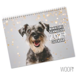 Op de afbeelding: Een spiraalgebonden wandkalender met een portret van een dwergschnauzer met een grijze en zwarte vacht. De hond heeft een open bek en staat tegen een lichtgrijze achtergrond met gouden bokeh-lichteffecten. De tekst luidt Miniature Schnauzer 2027 Calendar.