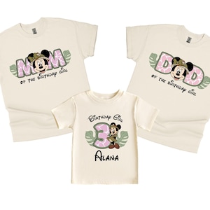 May include: Three beige t-shirts with a jungle theme featuring Mickey Mouse. The shirts say "Mom of the Birthday Girl", "Dad of the Birthday Girl", and "Birthday Girl" with a pink number 3.