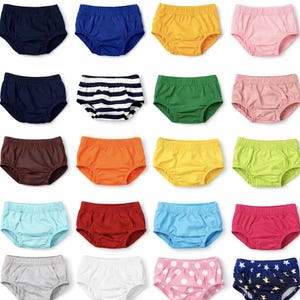 May include: A collection of colorful baby bloomers in various solid colors and patterns. The bloomers are displayed in rows, showcasing a range of hues including purple, blue, yellow, pink, green, orange, and white. Some bloomers feature stripes, polka dots, and nautical prints.
