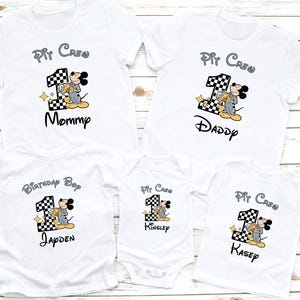 May include: Set of five white t-shirts with a Mickey Mouse pit crew theme. The shirts feature a black and white checkered number one, a Mickey Mouse character wearing a racing suit, and the text "Pit Crew". The shirts are personalized with the names "Mommy", "Daddy", "Jayden", "Kinsely", and "Kasey".