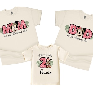 May include: Three cream-colored t-shirts with a pink and green jungle theme. One shirt says "Mom of the birthday girl" with a cartoon Minnie Mouse wearing a safari hat. Another shirt says "Dad of the birthday girl" with a cartoon Minnie Mouse wearing a safari hat. The third shirt says "Birthday Girl" with a cartoon Minnie Mouse wearing a safari hat and the number 2.