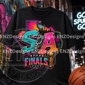 May include: A black t-shirt featuring a vibrant graphic of the state of Texas in neon colors. The design includes the letters SA, a basketball team logo, a city skyline, a championship trophy, and the text Spurs Finals 2026 in a bold font.