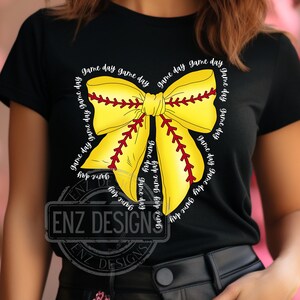 K&ouml;nnte beinhalten: Schwarzes T-Shirt mit einer gelben und roten Softball-Schleife. Die Schleife ist mit dem Text "game day" umrandet.