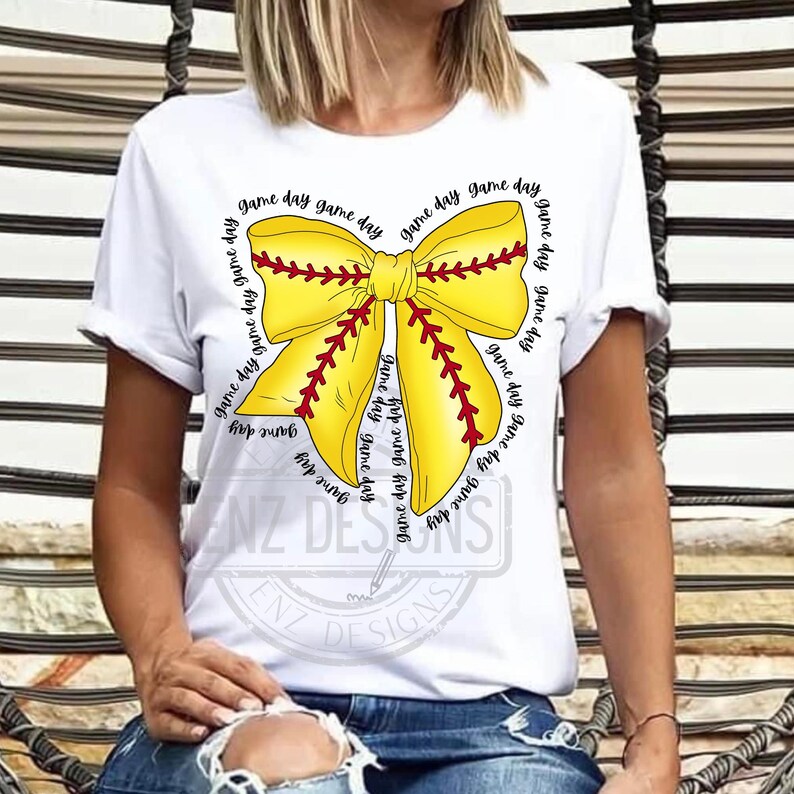 K&ouml;nnte beinhalten: Wei&szlig;es T-Shirt mit einer gelben und roten Baseball-Schleife mit dem Text "game day", der sich um die Schleife wiederholt.