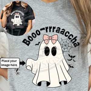 May include: A light gray t-shirt featuring a cartoon ghost with a pink bow, black eyes, and eyelashes. The text "Booo-rrraaccha" is above the ghost, with bats and a spiderweb. The shirt is a Halloween-themed design.