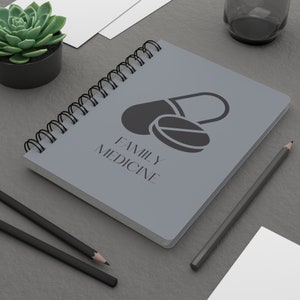 May include: A gray spiral bound notebook with the text "FAMILY MEDICINE" and a black silhouette of a pill on the cover.