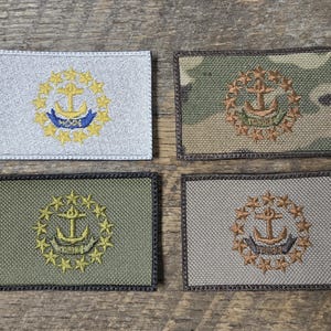 Op de afbeelding: Vier rechthoekige geborduurde patches met anker- en sterontwerpen. De patches zijn in verschillende kleuren, waaronder zilver, camouflage, olijfgroen en grijs. Het anker is omgeven door een krans van sterren.