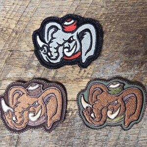 May include: Three embroidered patches featuring a cartoon elephant with a hat. The top patch is gray, red, and black. The bottom left patch is brown and tan. The bottom right patch is brown and green.