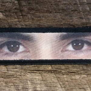 Pode incluir: Close-up de um par de olhos castanhos com cílios e sobrancelhas escuras. Os olhos estão olhando diretamente para o espectador.