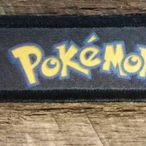 May include: Black patch with a yellow "Pokémon" logo and two red and white Poké Balls on either side.