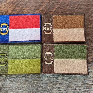 May include: Four rectangular patches with embroidered designs. One patch features a blue field with a gold emblem and red and white stripes. The other three patches have two-tone color schemes of brown, tan, green, and olive.