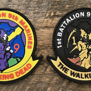 May include: Two circular morale patches featuring a grim reaper figure holding a scythe. The left patch has a yellow border, blue background, and purple reaper. The right patch is black and gold. Both feature the text 1st BATTALION 9th MARINES and THE WALKING DEAD.