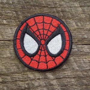May include: Red and black embroidered patch of Spider-Man's mask. The mask is white with black outlines and a red spider web design.